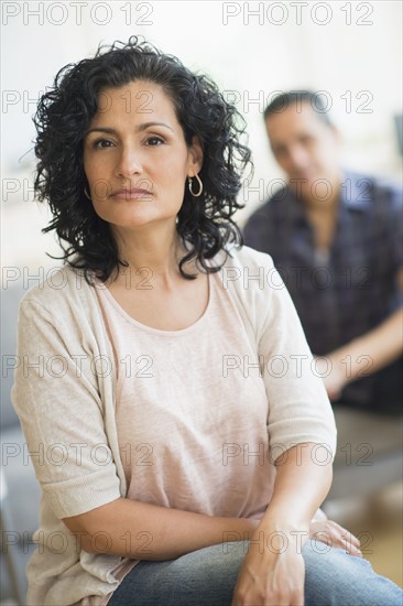 Portrait of woman with man in background.