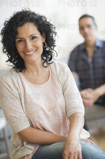 Portrait of smiling woman with man in background.