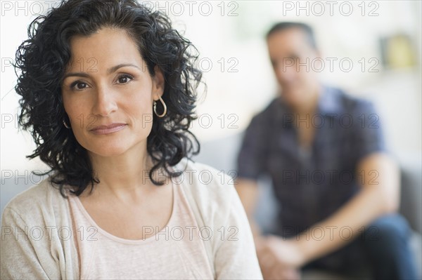 Portrait of woman with man in background.