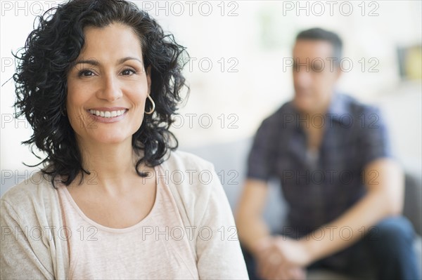 Portrait of smiling woman with man in background.