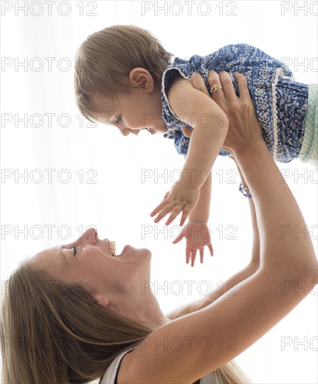 Mother lifting up baby daughter (18-23 months).