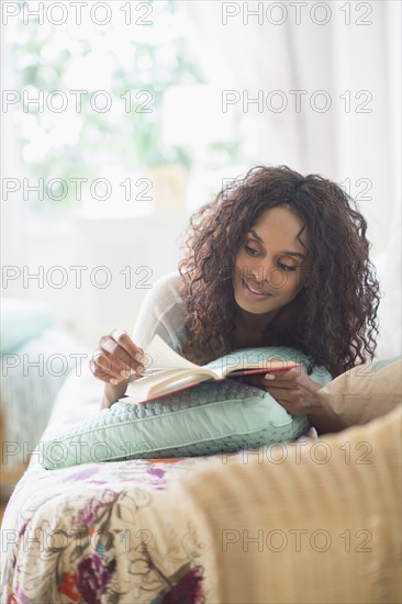 Woman reading book on bed.