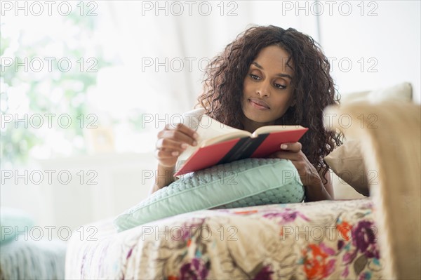 Woman reading book on bed.