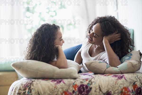 Mother with daughter (8-9) talking on bed.