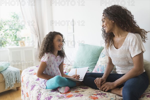 Girl (8-9) using digital tablet on bed.