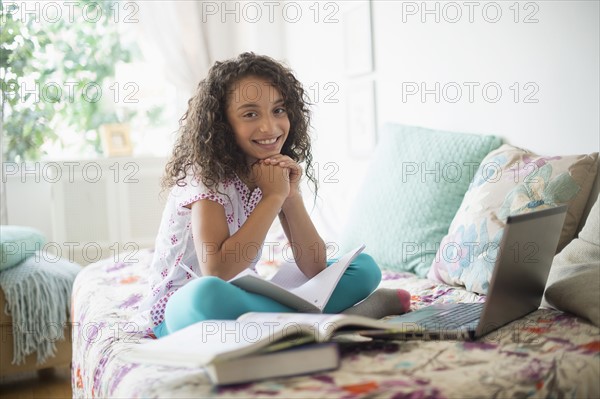 Girl (8-9) studying on bed.