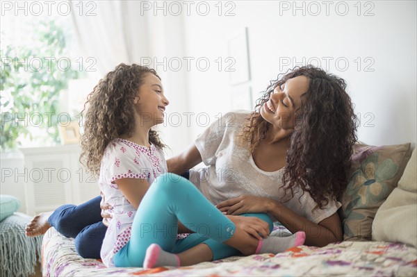 Mother and daughter (8-9) sitting on bed.