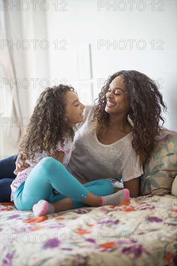 Mother and daughter (8-9) sitting on bed.