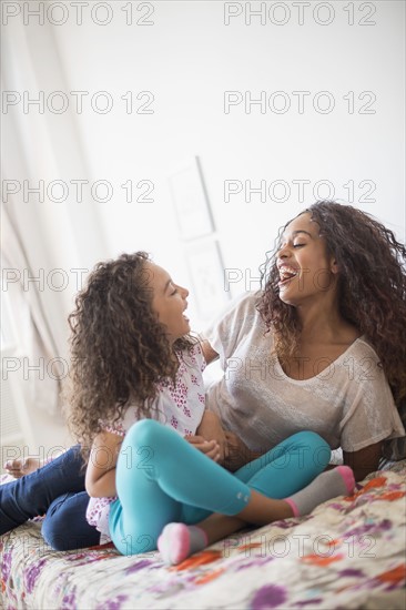 Mother and daughter (8-9) sitting on bed.