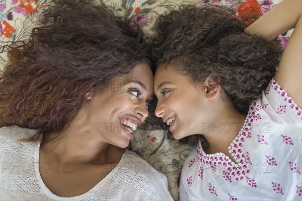 Mother and daughter (8-9) lying on bed.