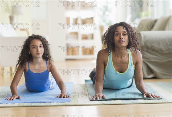 Mother and daughter (8-9) exercising in living room.