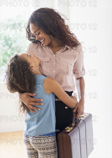 Mother walking in home, daughter (8-9) welcoming her.