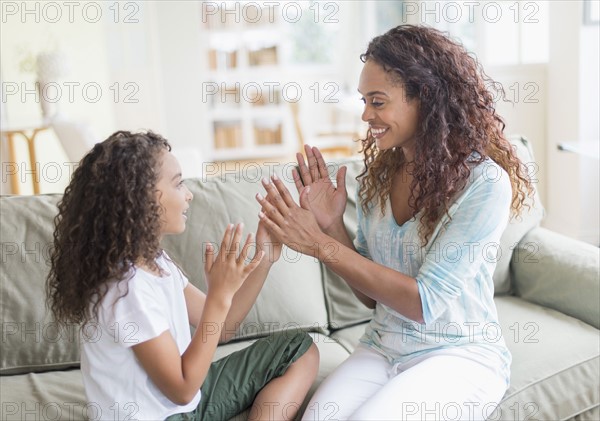 Daughter (8-9) and mother playing clapping game .