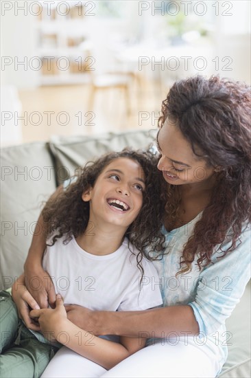 Mother embracing daughter (8-9) in living room.