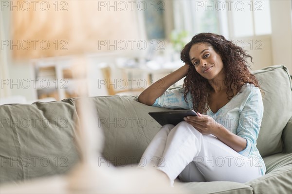 Woman using digital tablet on sofa.