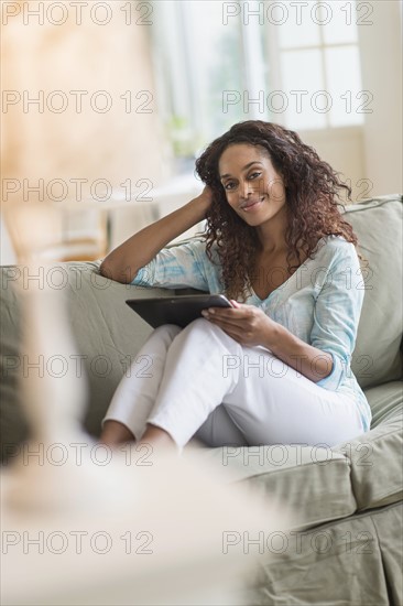 Woman using digital tablet on sofa.