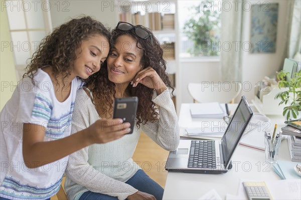 Daughter (8-9) and mother looking at smart phone.