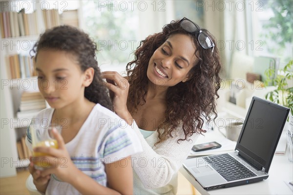 Woman braiding (8-9) daughter's hair.