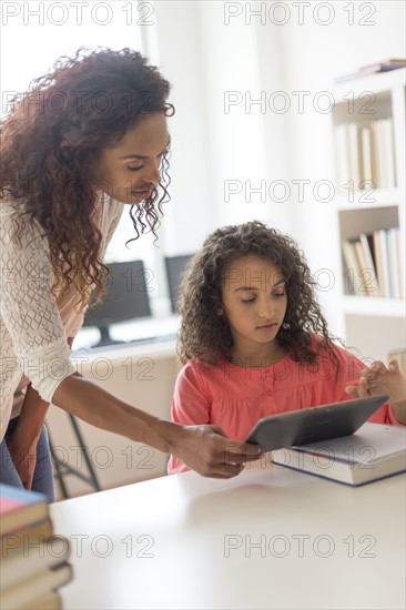 Girl (8-9) and teacher using digital tablet in classroom.