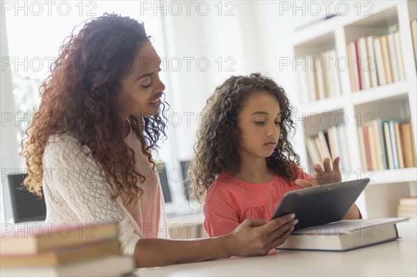 Girl (8-9) and teacher using digital tablet in classroom.