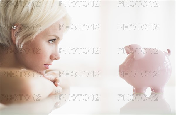 Woman staring at piggy bank.