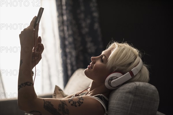 Woman lying on sofa using digital tablet.