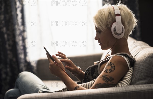 Woman sitting on sofa using digital tablet.