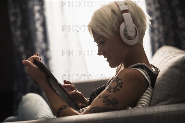 Woman sitting on sofa using digital tablet.