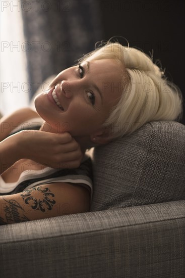 Portrait of blonde woman relaxing on sofa.