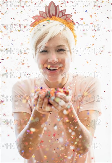 Woman wearing tiara blowing confetti.