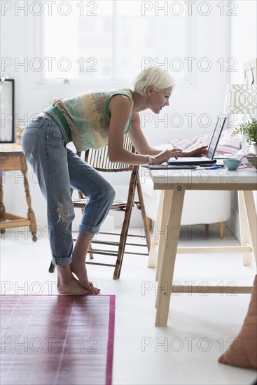 Woman using laptop and at home.
