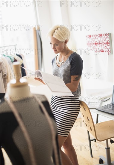 Designer looking at sketchbook in studio.