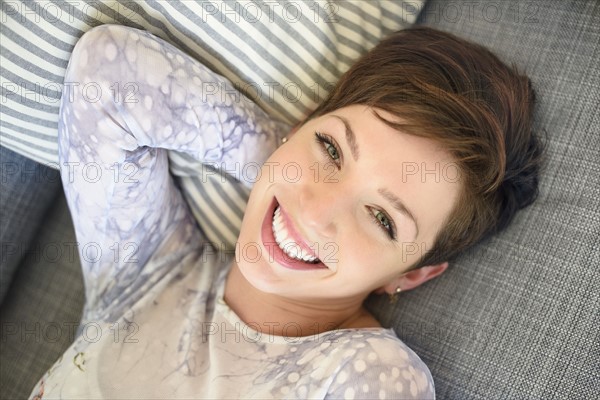 Portrait of smiling woman lying on sofa.