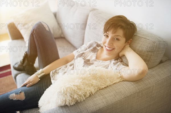 Portrait of smiling woman sitting on sofa.