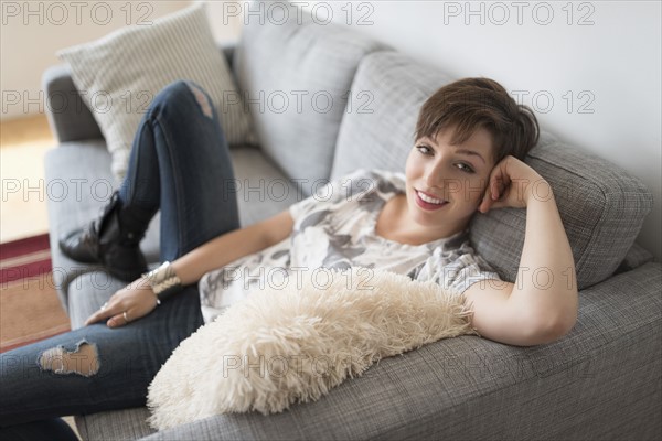 Portrait of smiling woman sitting on sofa.