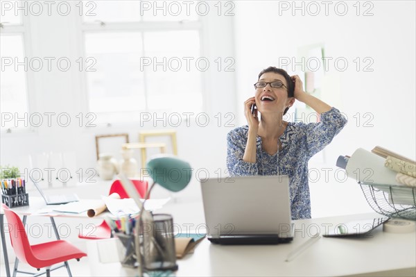 Senior business woman using cell phone in office.