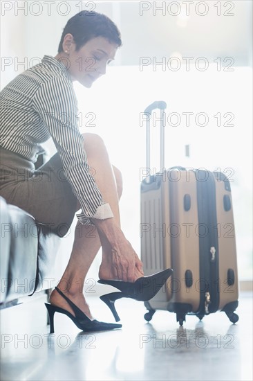 Businesswoman at the airport adjusting shoe.