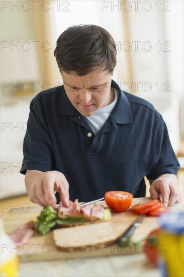 Man with down syndrome making sandwich.