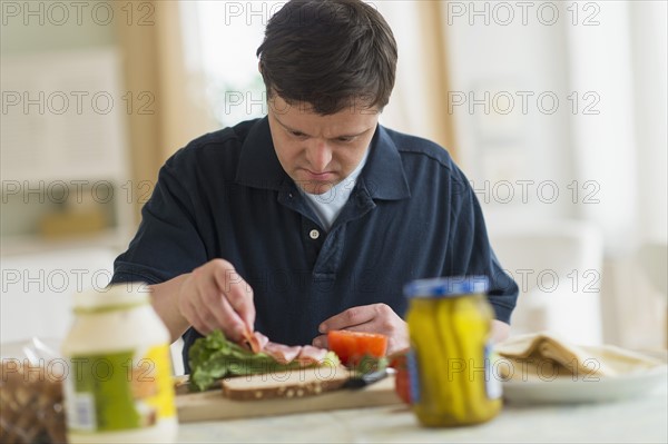 Man with down syndrome making sandwich.
