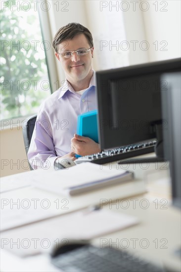 Man with down syndrome working in office.