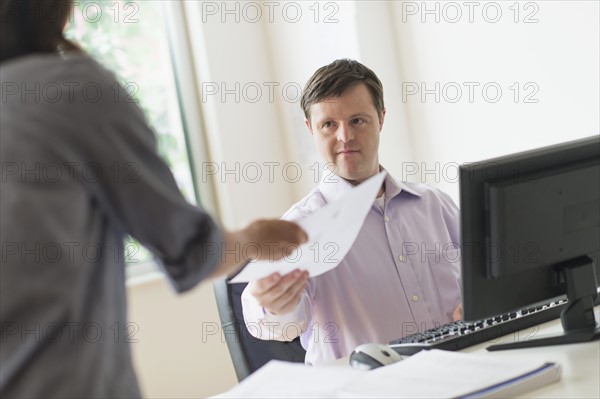 Man with down syndrome working in office.