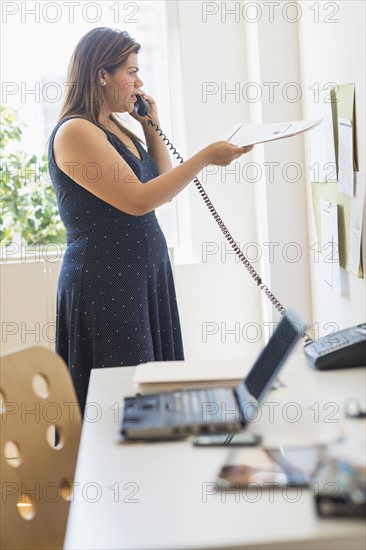 Woman using telephone in office.