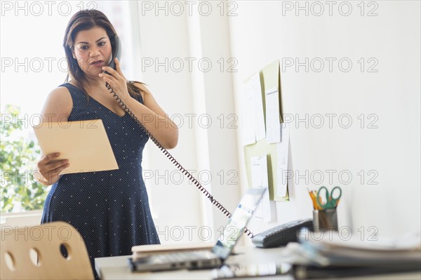 Woman using telephone in office.