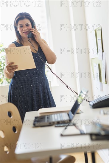 Woman using telephone in office.