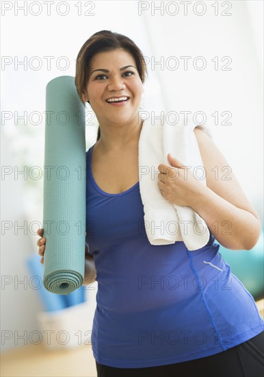 Woman holding exercise mat at gym.