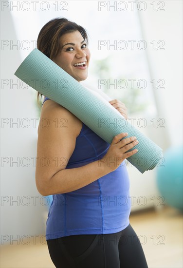 Woman holding exercise mat at gym.