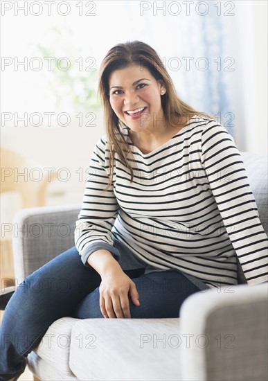 Portrait of happy woman sitting on sofa.