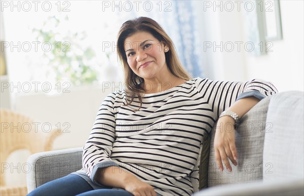 Portrait of happy woman sitting on sofa.