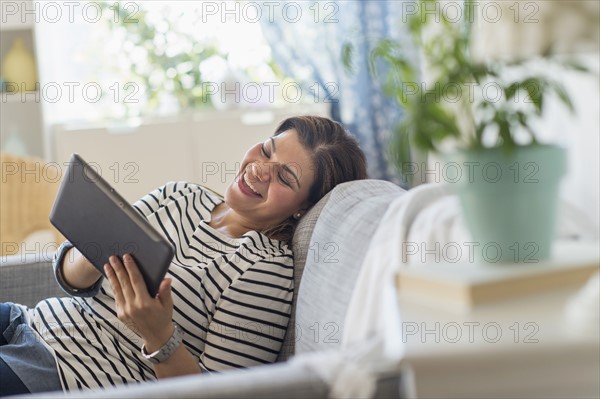 Portrait of happy woman lying on sofa with tablet pc.