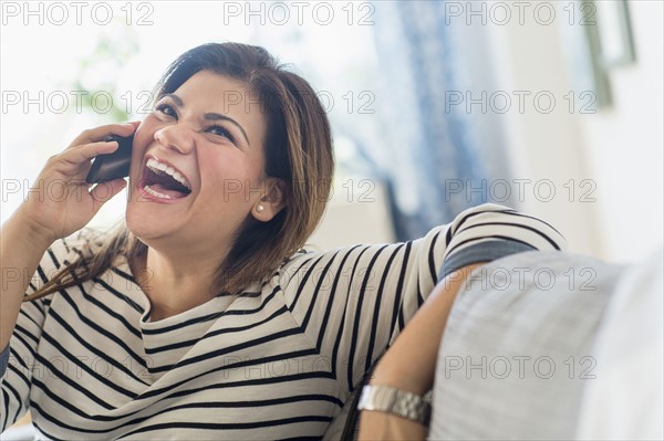 Happy woman sitting on sofa with mobile phone.